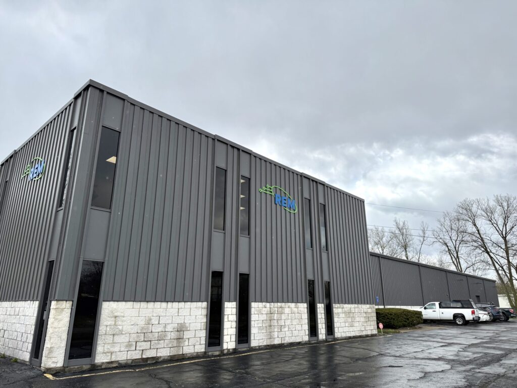 REM industrial facility exterior with company signage on gray metal building